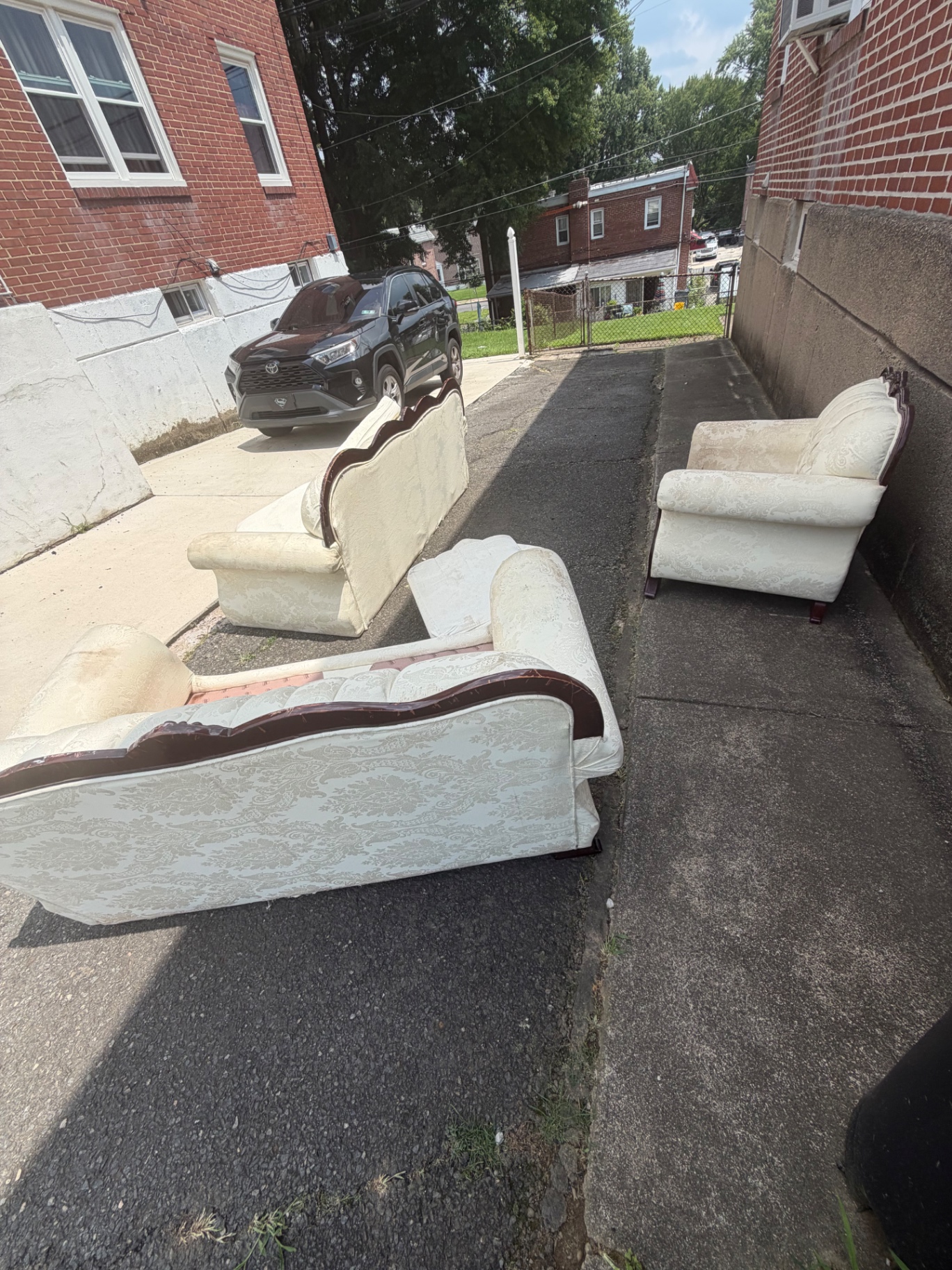Three old damask couches and armchairs left in a Philadelphia driveway for B.L.O.O.M. Entity pickup