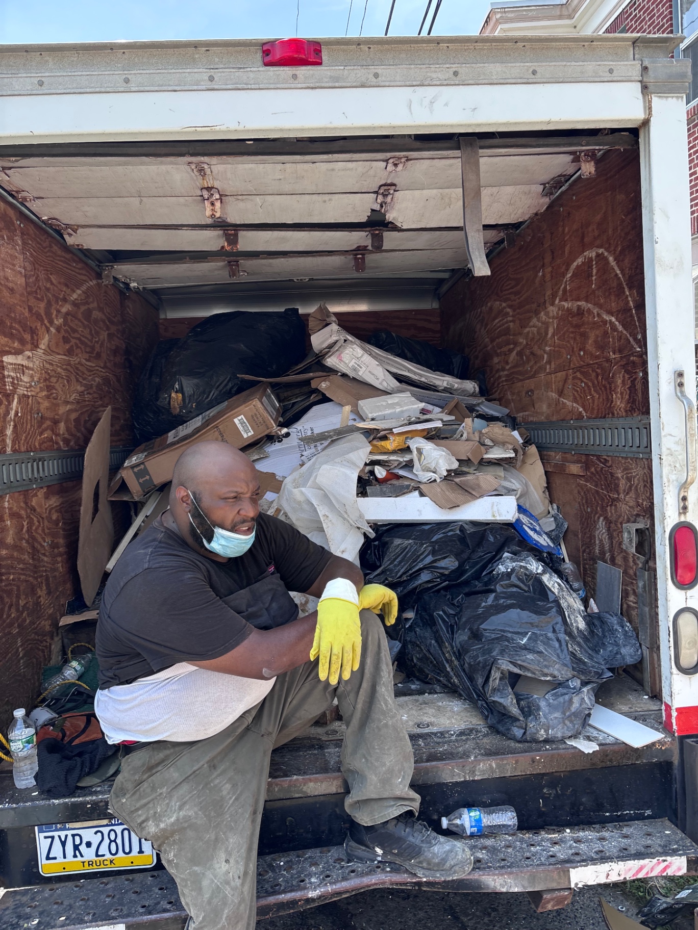 B.L.O.O.M. Entity crew member next to a fully loaded junk removal truck